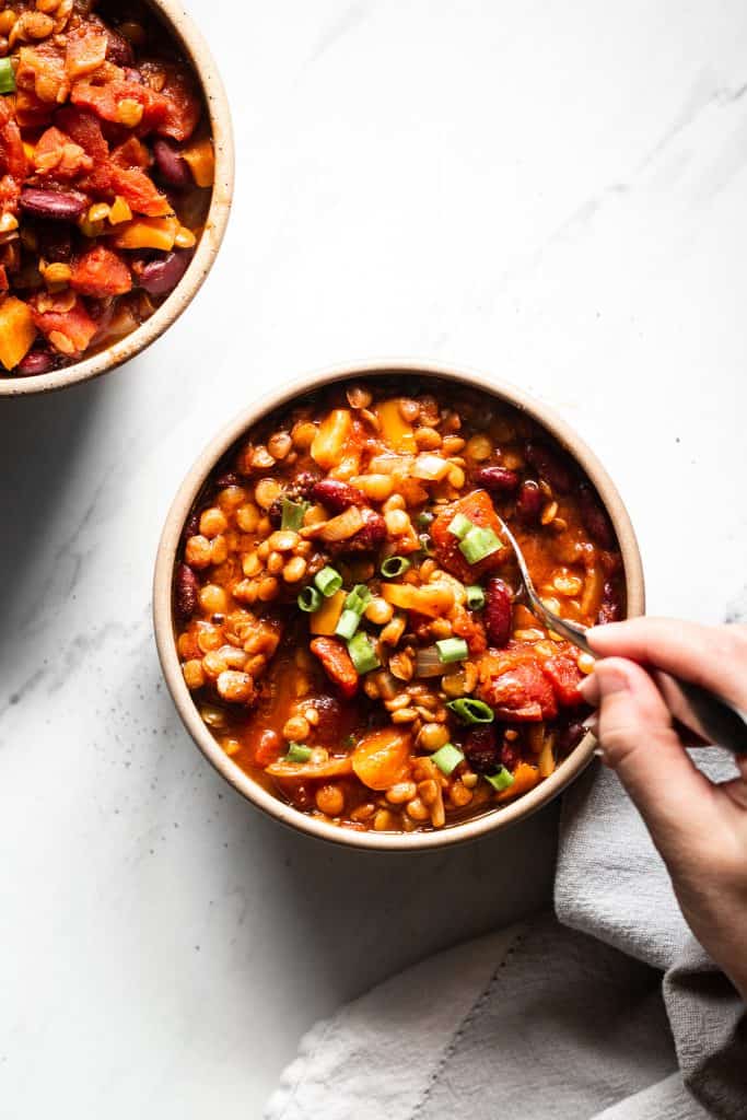 chili in a bowl and hand holding spoon