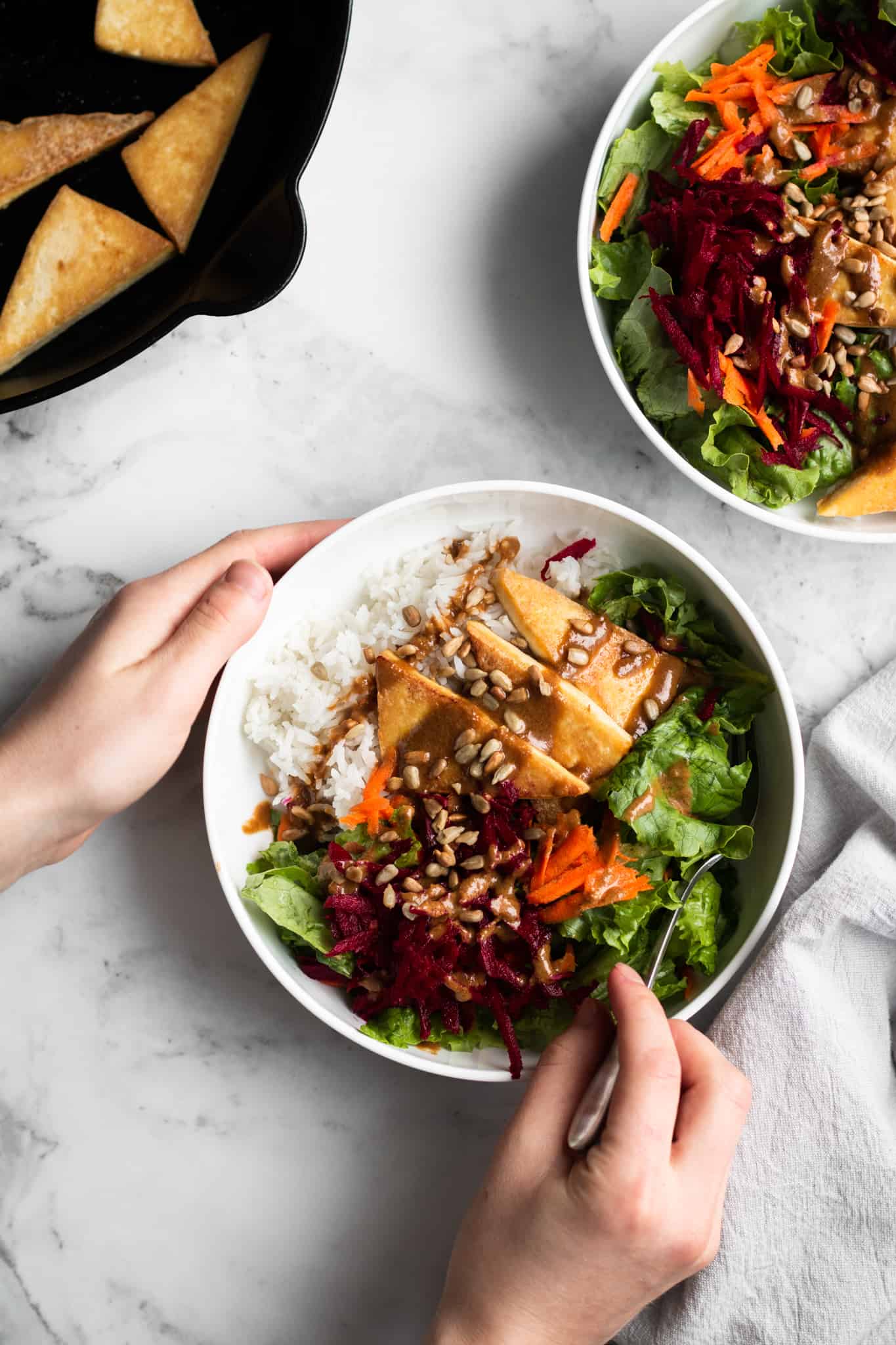 hands holding a bowl of cozy winter salad with tofu and rice